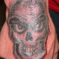 Tattoo von fürchterlichem glatzköpfigem Monster mit großen Zähnen an der Hand