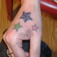 Tatuaje en la mano, tres estrellas de colores diferentes