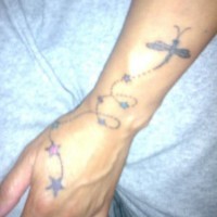 Delicato tatuaggio sul braccio: la libellula e le stelle sul filo
