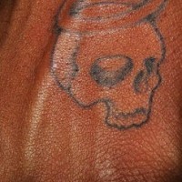 Tatuaje en la mano, cráneo con halo y sin la mandíbula inferior
