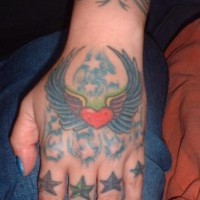 Tatuaje en la mano, corazón con alas, montón de estrellas