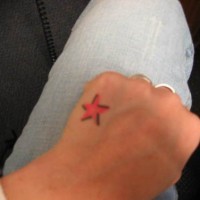 Little, bright, red , juicy star hand tattoo