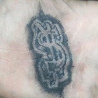 Un signe de dollar volumétrique le tatouage sur la paume à l'encre noir