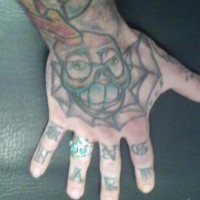 La faccia che sorride, la ragnatela tatuati sulla mano e segni tatuati sulle dita