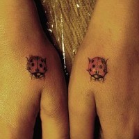 Tattoo von zwei farbigen kleinen  Marienkäfern an Händen
