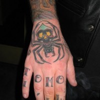 Grande ragno nero tatuato sulla mano e le lettere su ogni dito tatuate
