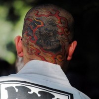 Kopf Tattoo mit bärtigem, faltigem Monster, im Feuer