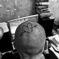 Le cœur épinglé par la flèche tatouage sur la tête à l'encre noir