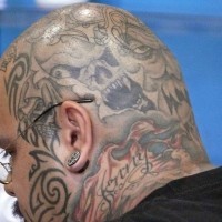Tattoo von verschiedenen stilisierten Monstergesichten und Inschrift 