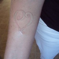 Le tatouage d'entrelacs en forme de cœur à l'encre blanc