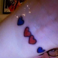 tatuaje en la muñeca de corazones rojos y azules