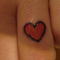 Tattoo von kleinem rotem glänzendem  Herzchen an Fingerknöcheln