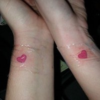 Le tatouage similaire de cœurs roses sur le poignet