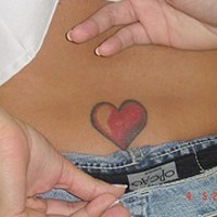 Small red heart tattoo on lower back