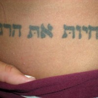 tatuaje en tinta negra en la cadera de hebreo