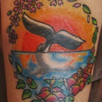 Le tatouage de la queue de baleine au soleil couchant encadré de fleurs