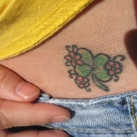 Tatuaje en la cadera, trébol y tres flores diminutas