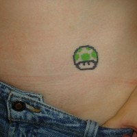 Tatouage sur la hanche de petit tête verte d'un personnage de la jeu