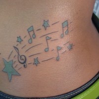 Tattoo von blauen feinen Noten, Sternen, G-Schlüssel auf Notenlinien  an der Hüfte