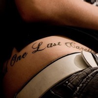 Une longue inscription en italique tatouage sur la hanche aux  grandes lettres