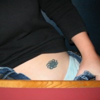 Round little sign, toothed flower hip tattoo