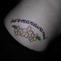 Tatuaje en la cadera, inscripción en otro idioma sobre flores