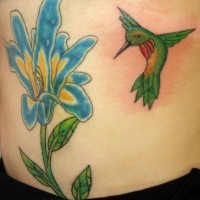 Green hummingbird on blue flower tattoo