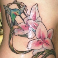 Elegant hummingbird on pink flowers tattoo