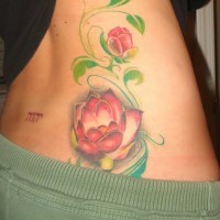 el tatuaje de unas flores de loto en color rosa y hojas verdes hecho en el costado