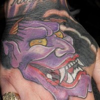 Tattoo von fürchterlichem lila Monster mit großen Zähnen in japanischem Stil an der Hand