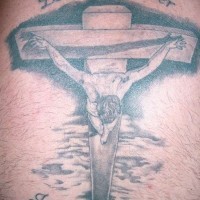 Tatuaje de Jesús crucificado y una frase