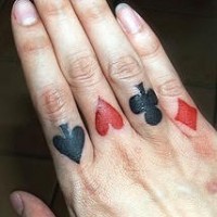 Tattoo von Spielkartenzeichen an Fingerknöcheln