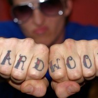 Un mot à gros lettres le bois dur tatouage sur les phalanges