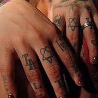 Tattoo von Lettern, Herzen und vielen anderen Zeichen  an Fingerknöcheln