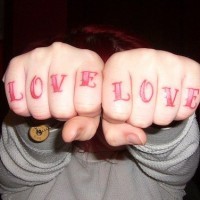 Tatouage sur les phalanges de mot l'amour à l'encre rouge