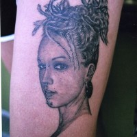 Une belle fille aux cheveux fendus avec un piercing tatouage sur la jambe
