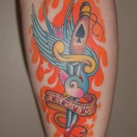 Tatuaje en la pierna, ave azul que lleva letrero en el pico, cuchillo, fuego