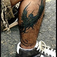 L'uccello-dragone colorato tatuato sulla gamba