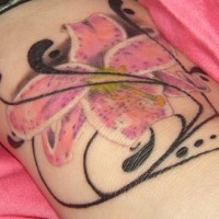 Tatuaje de lirio color rosa y una tracería