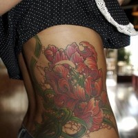 Un gros tatouage détaillé de fleur de lys sur le flanc