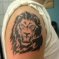 El tatuaje tribal de la cabeza de un leon rugiendo en color negro en el brazo o hombro