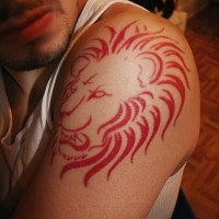 El tatuaje de la cabeza de un leon rojo rugiendo en el brazo o hombro