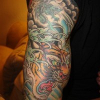 El tatuaje asiatico en color de un tigre rugiendo en el brazo o hombro