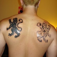 los tatuajes simetricos blanco y otro negro de dos leones heraldicos en la espalda