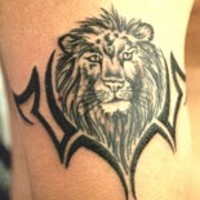 El tatuaje de la cabeza de un león negro con un brazalete de tribal