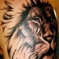 El tatuaje de la cabeza de un león hermoso con ojos de color en el hombro