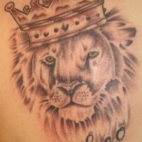 Green eyed lion in crown tattoo