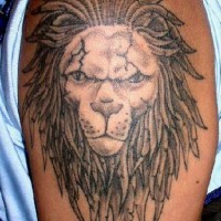 El tatuaje de la cabeza de un leon con rastas en el hombro o brazo