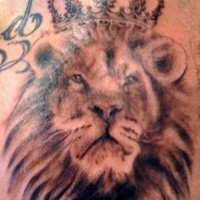 El tatuaje de la cabeza de un leon con una corona hecho con tinta negra