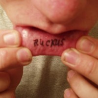 Lip tattoo, ruckus, big, thin , black letters